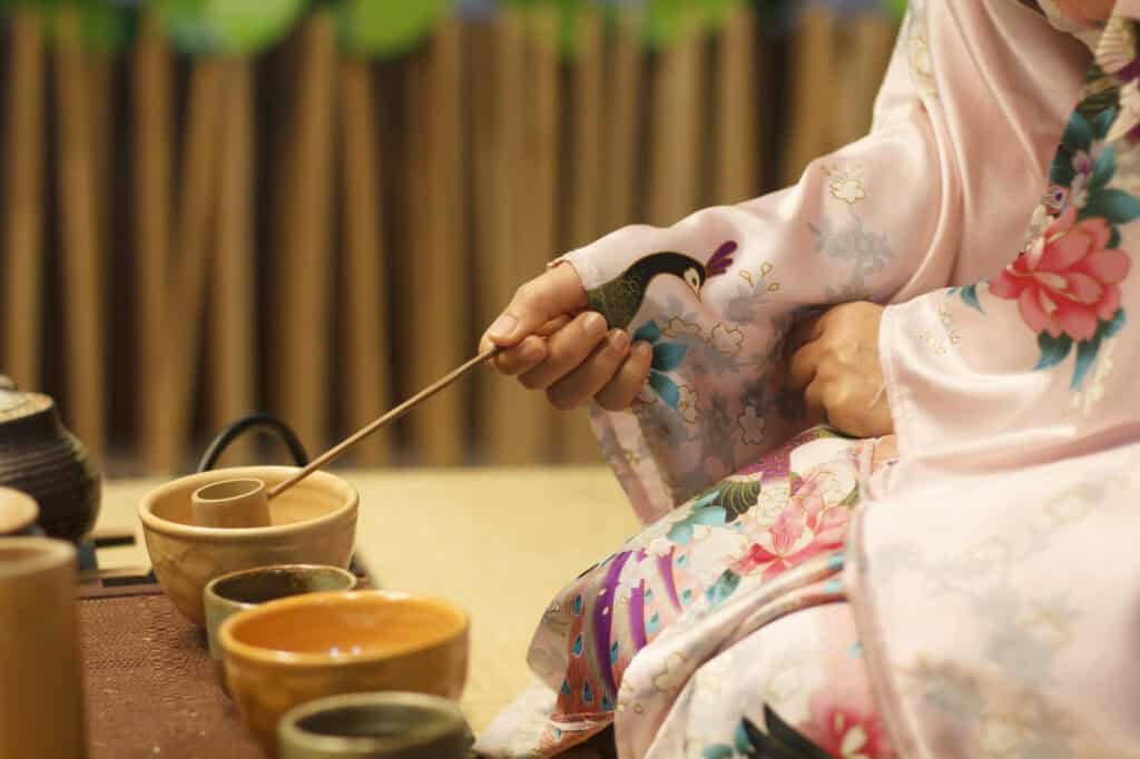 Guests in kimono at a Japanese tea ceremony with tea bowls and utensils