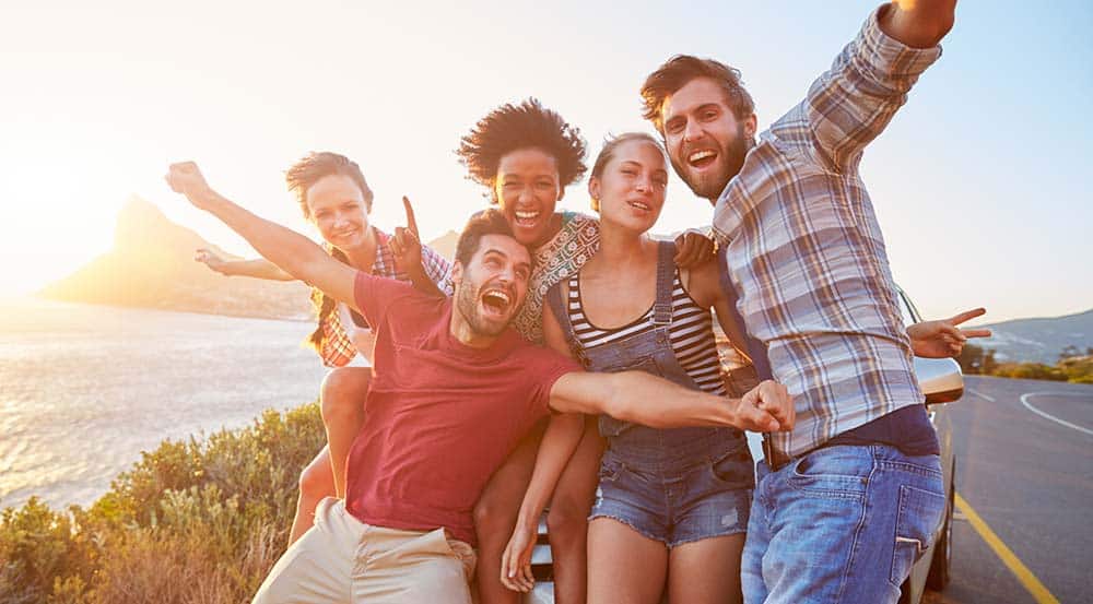 A group of young friends laughing and posing together outdoors at sunset