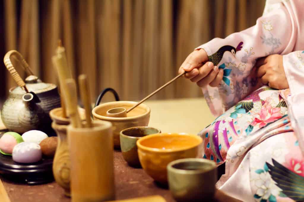 Colorful tea bowls and a host in kimono at a tea gathering