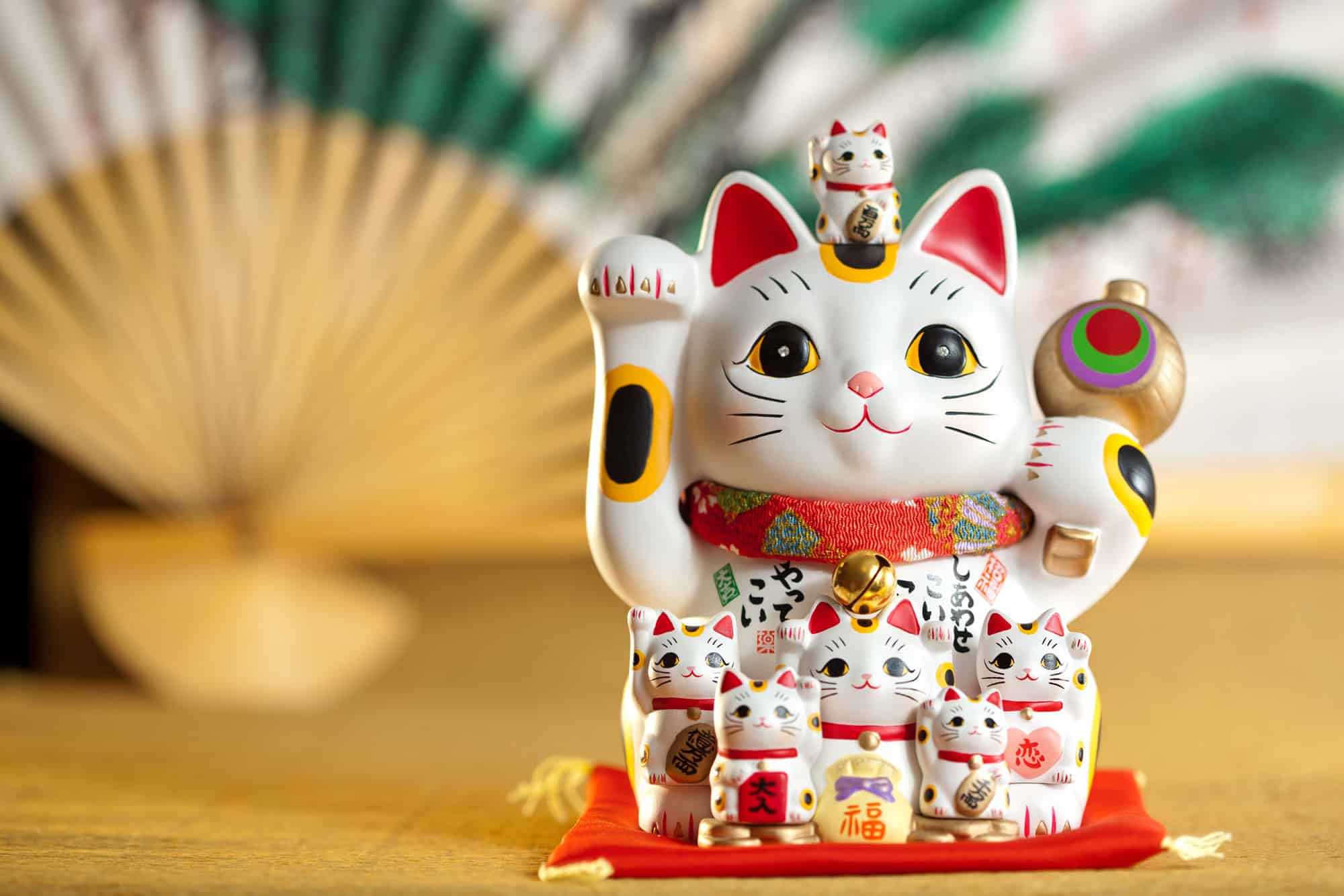 A group of maneki-neko lucky cat figurines with raised paws