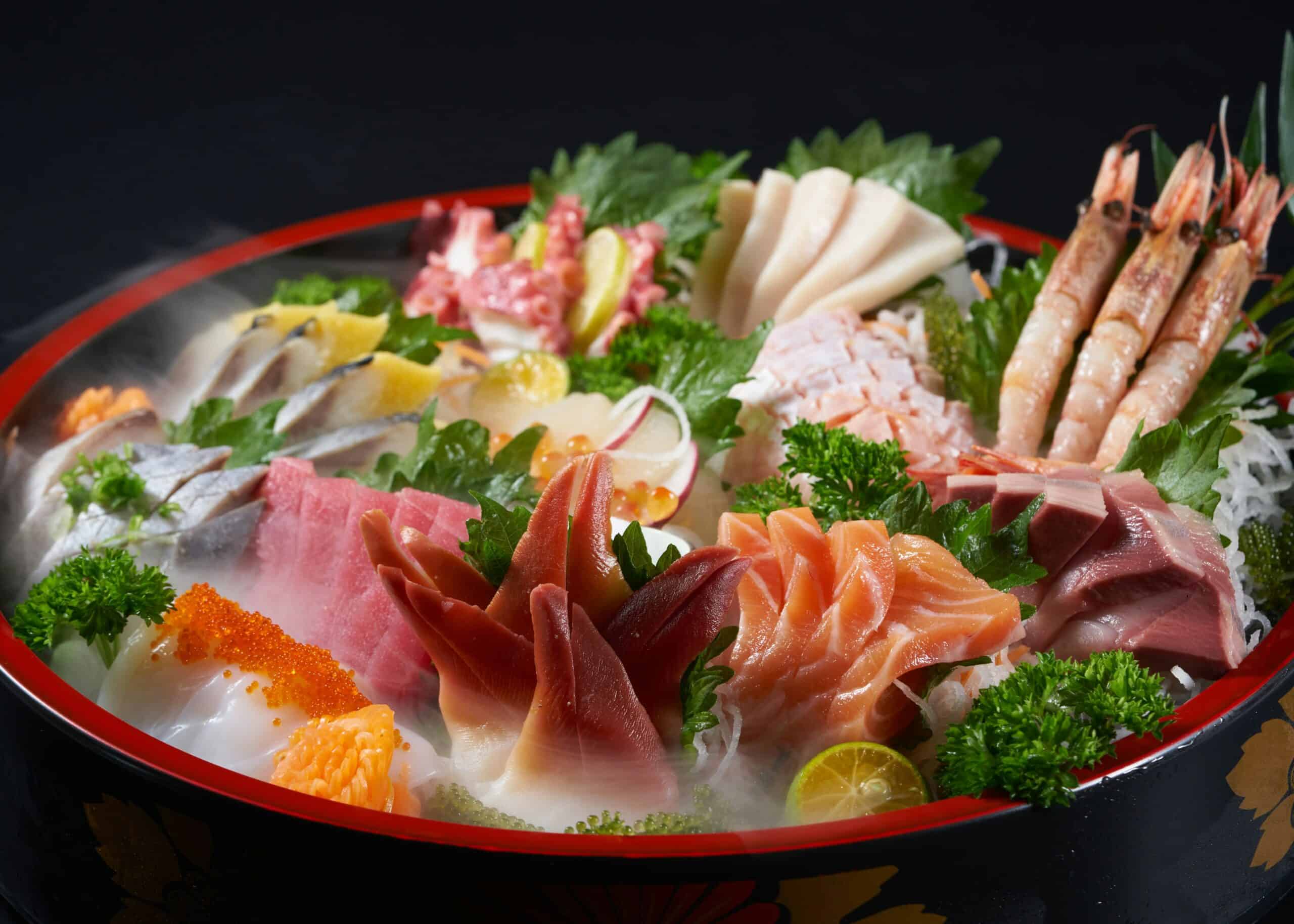 A red and black lacquer bowl piled with sashimi, shrimp and salmon roe for a celebration