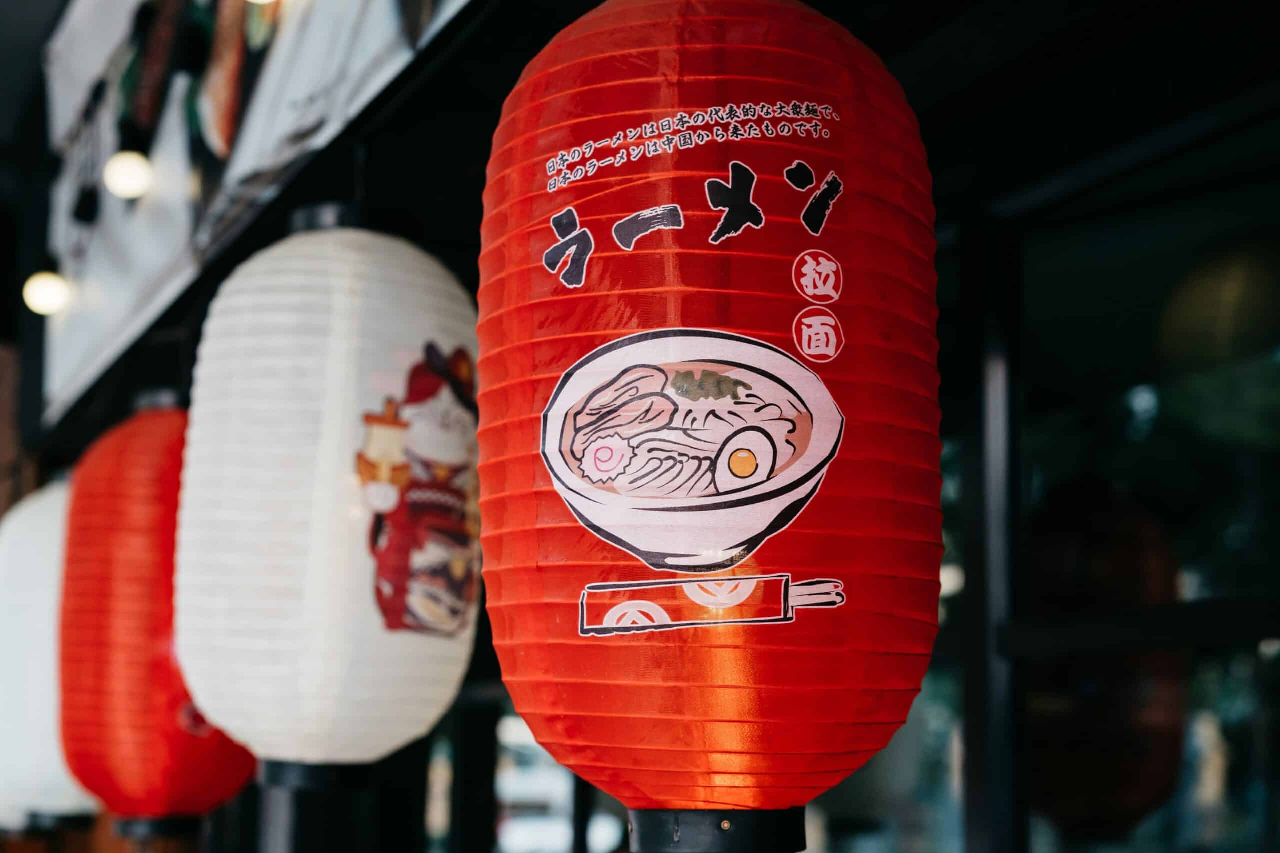 Red paper lantern with a ramen illustration and Japanese characters, the kind of sign that sends travelers looking for how to start learning kanji