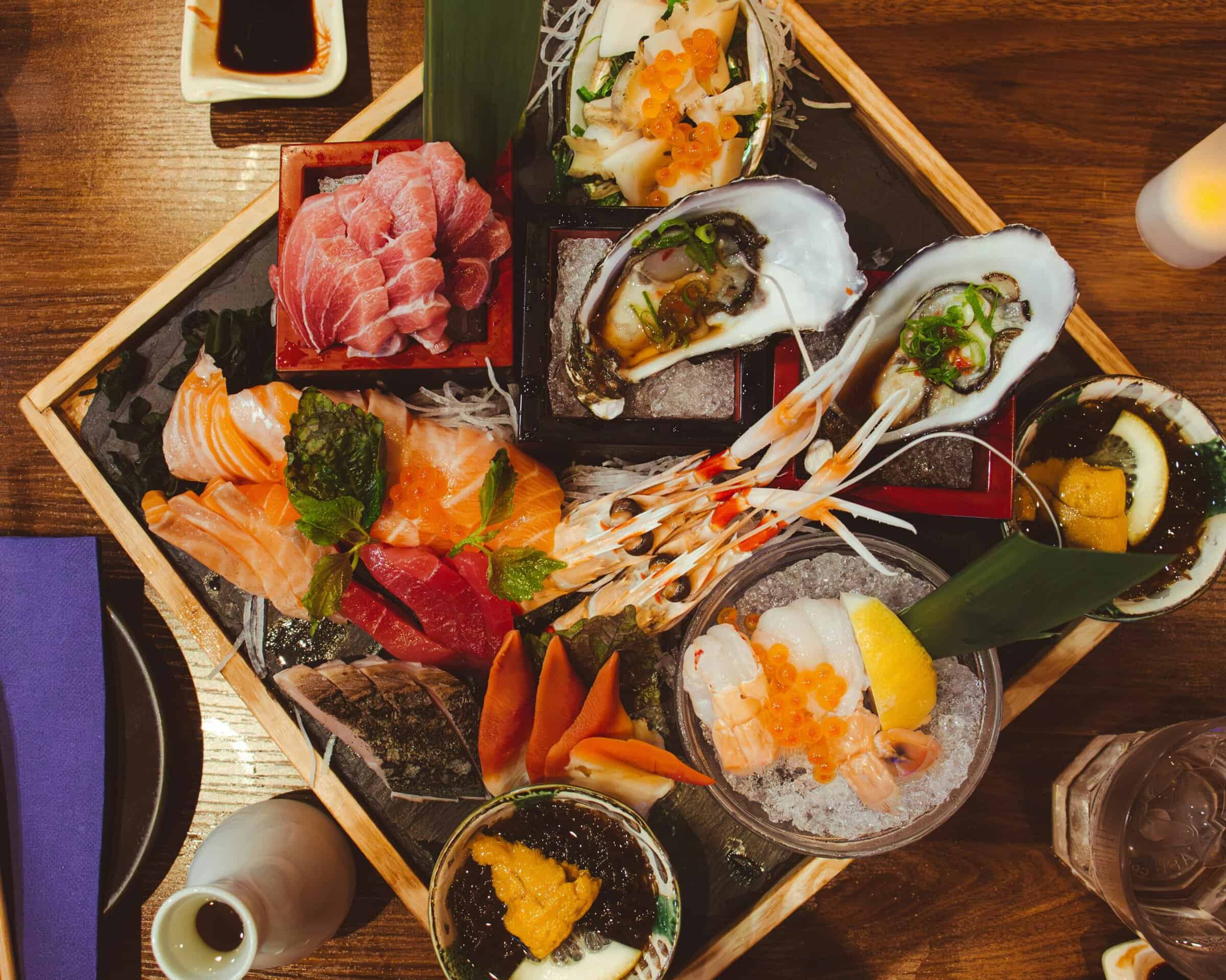 A wooden box of New Year seafood with shrimp, oysters, sashimi and salmon roe seen from above