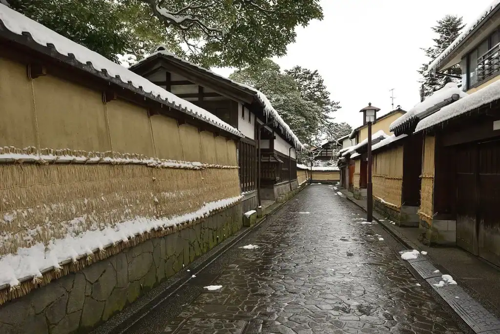 A snow-dusted lane in Kanazawa's Nagamachi samurai district, lined with earthen walls and wooden houses