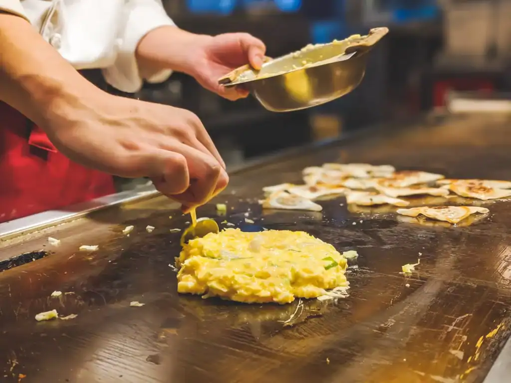 Batter cooking on a hot griddle at a Tokyo restaurant table