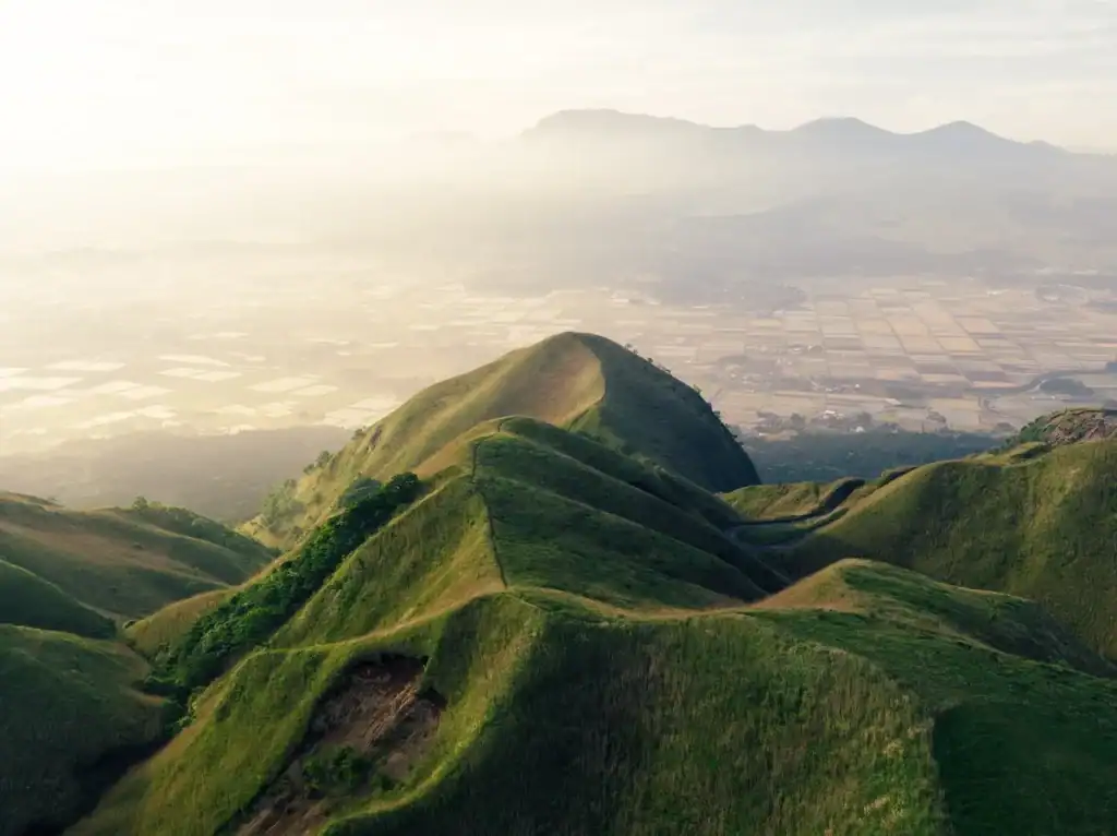 Green mountain ridges rolling toward a wide valley under soft morning light