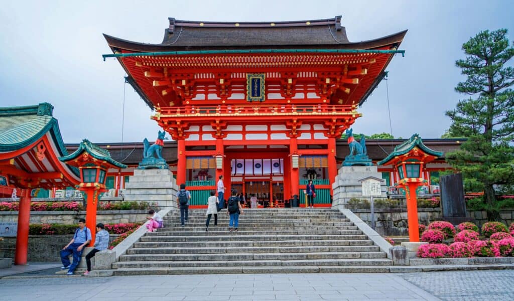 The vermilion two-story gate of Fushimi Inari in Kyoto above wide stone steps under a blue sky