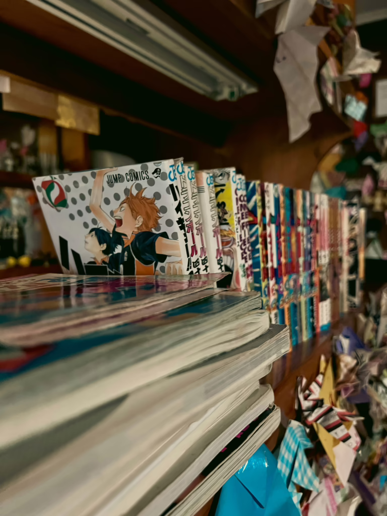 Stacks of manga volumes on a shelf in a Japanese bookstore