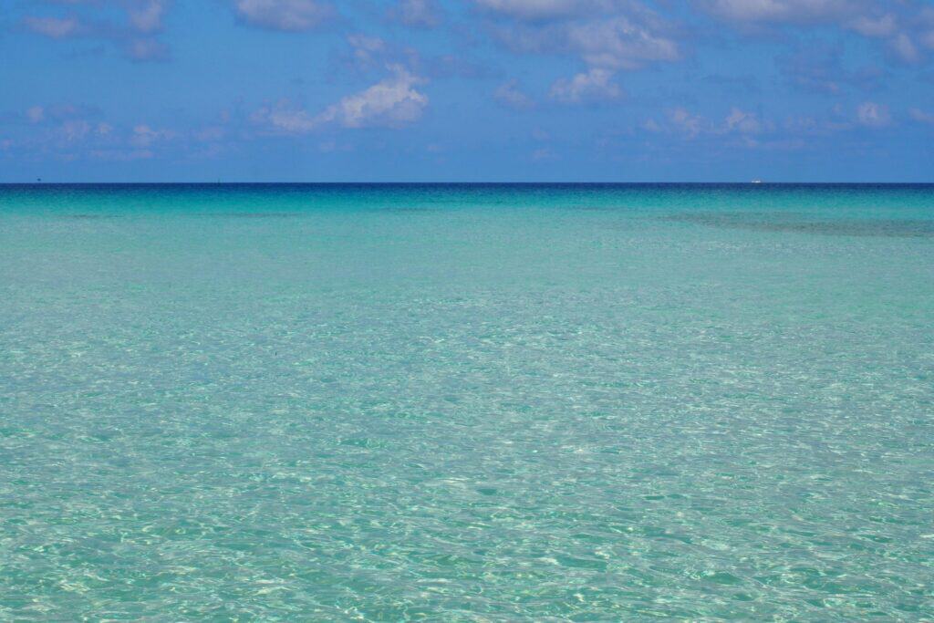 Clear turquoise water stretching to the horizon under a blue sky off an Okinawan island