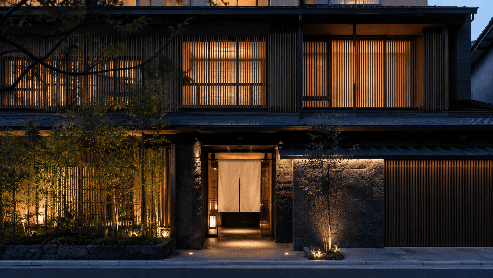 A traditional Japanese inn at dusk with warm lantern light, opening 2026
