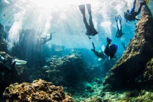 Scuba divers exploring a colorful coral reef in Japan, showcasing marine life and underwater scenery.