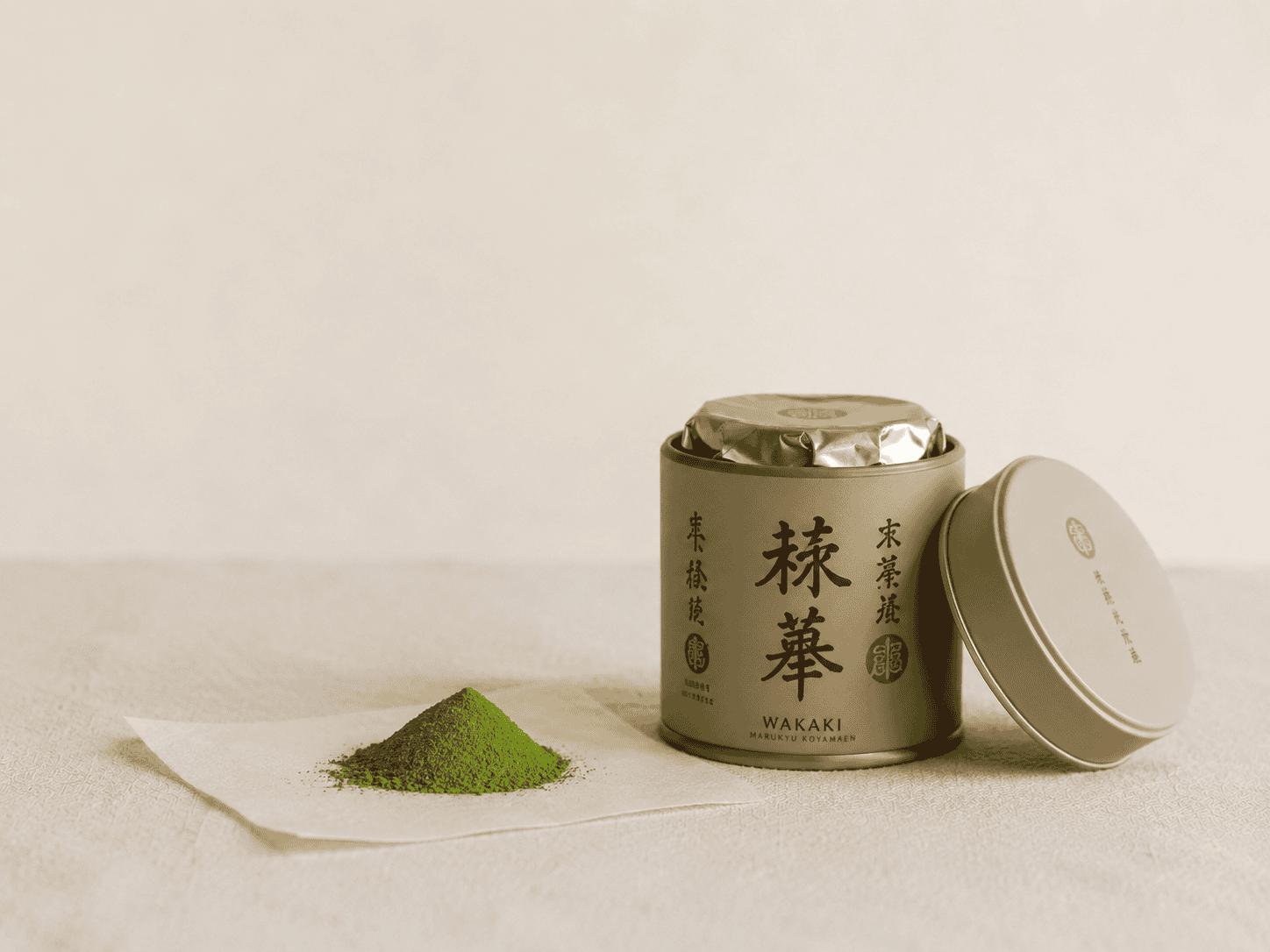 Japanese matcha powder in a decorative tin with green powder on paper.