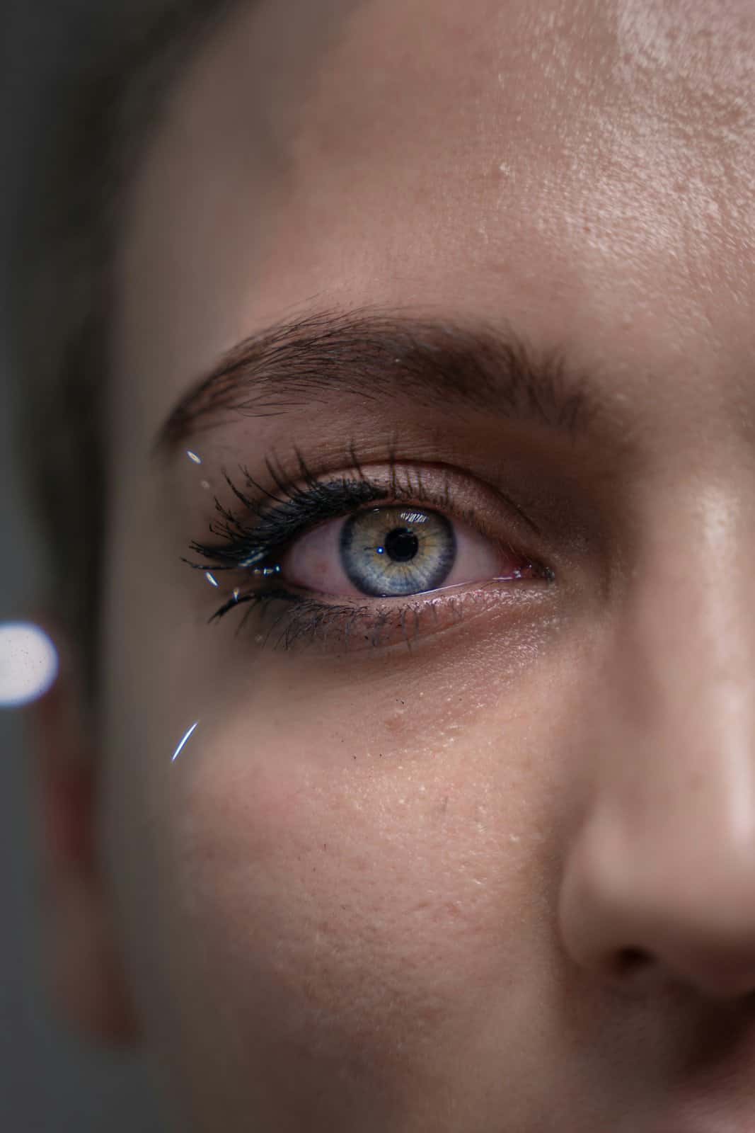 Close-up of a woman's pale blue eye with damp lashes, the instant mono no aware missing someone begins
