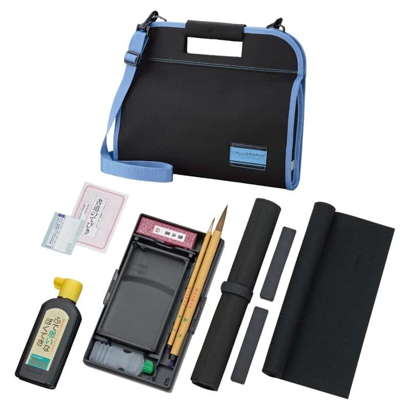 A Kuretake two-way calligraphy set with a blue-trimmed carry case, brushes, ink, inkstone and felt mat