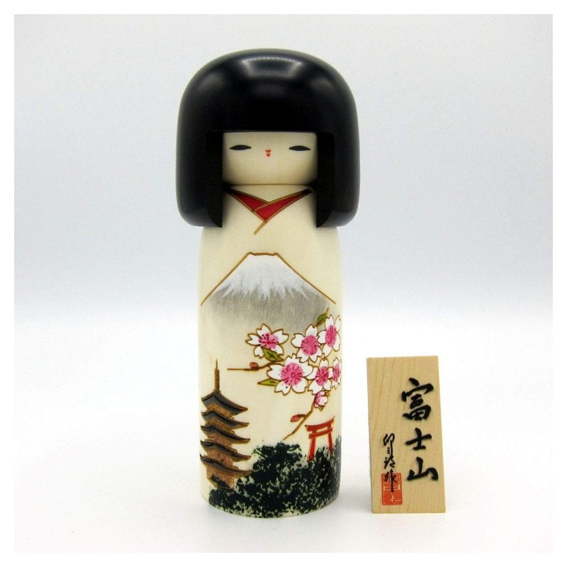A Usaburo kokeshi doll painted with Mount Fuji, a pagoda and cherry blossoms on a white body