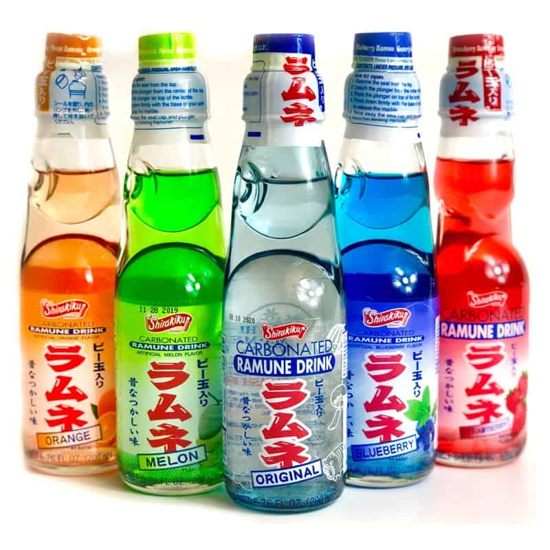 Five glass bottles of Ramune soda in different colors and flavors