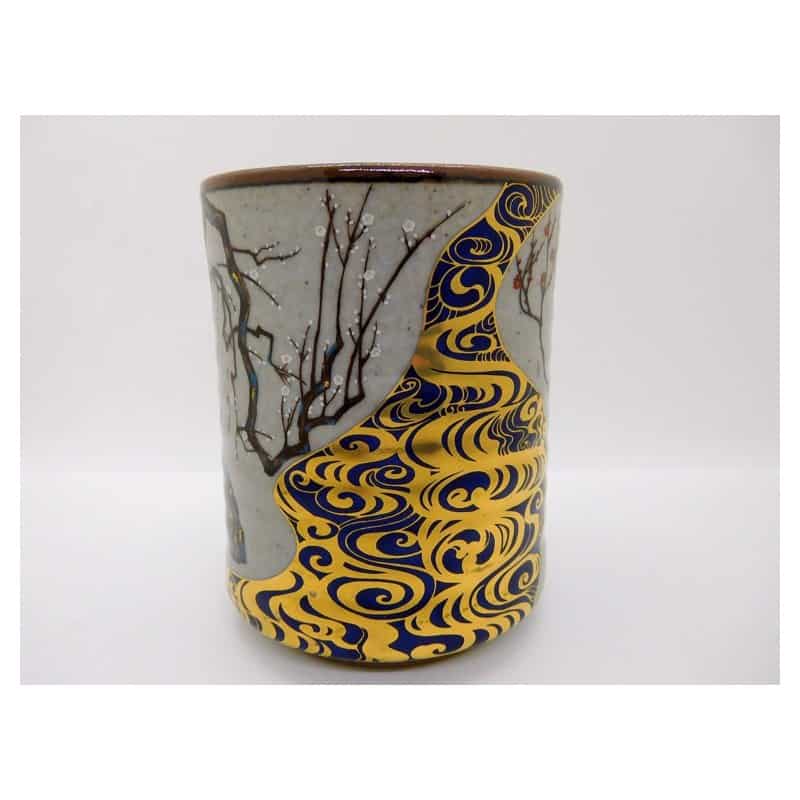A Kutani-ware teacup painted with gold plum blossoms on a dark glaze