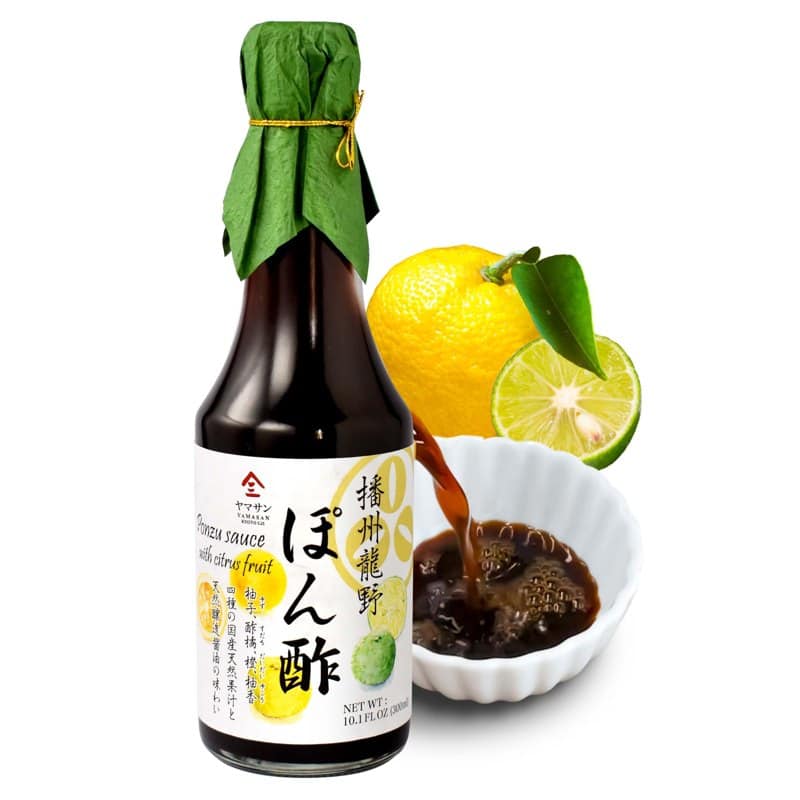 A bottle of Yamasan Kyoto Uji yuzu ponzu with a fresh yuzu fruit and a bowl of sauce