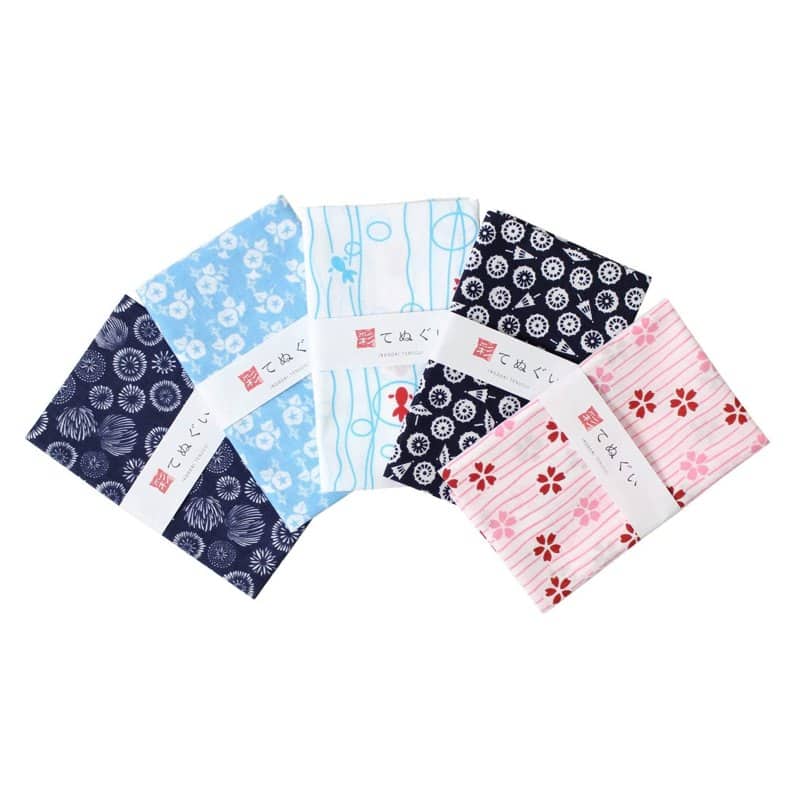 Five folded Komesichi tenugui cotton towels in blue, pink and white traditional patterns