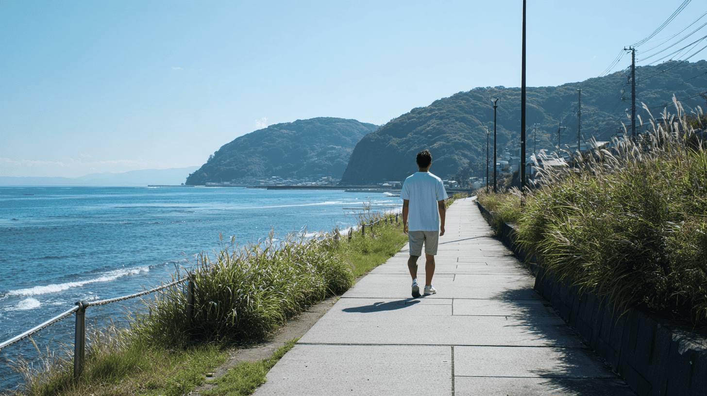 A man walking alone along a sunny seaside path in Kamakura in the morning, relaxed, seen from behind