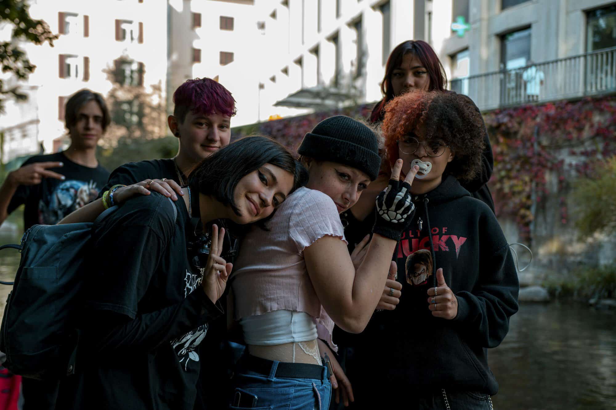 A group of smiling teenage friends posing together beside a city canal